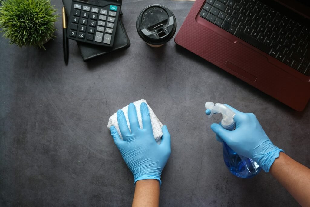 Reinigung einer Arbeitsfläche mit Handschuhen, Sprühflasche und Tuch